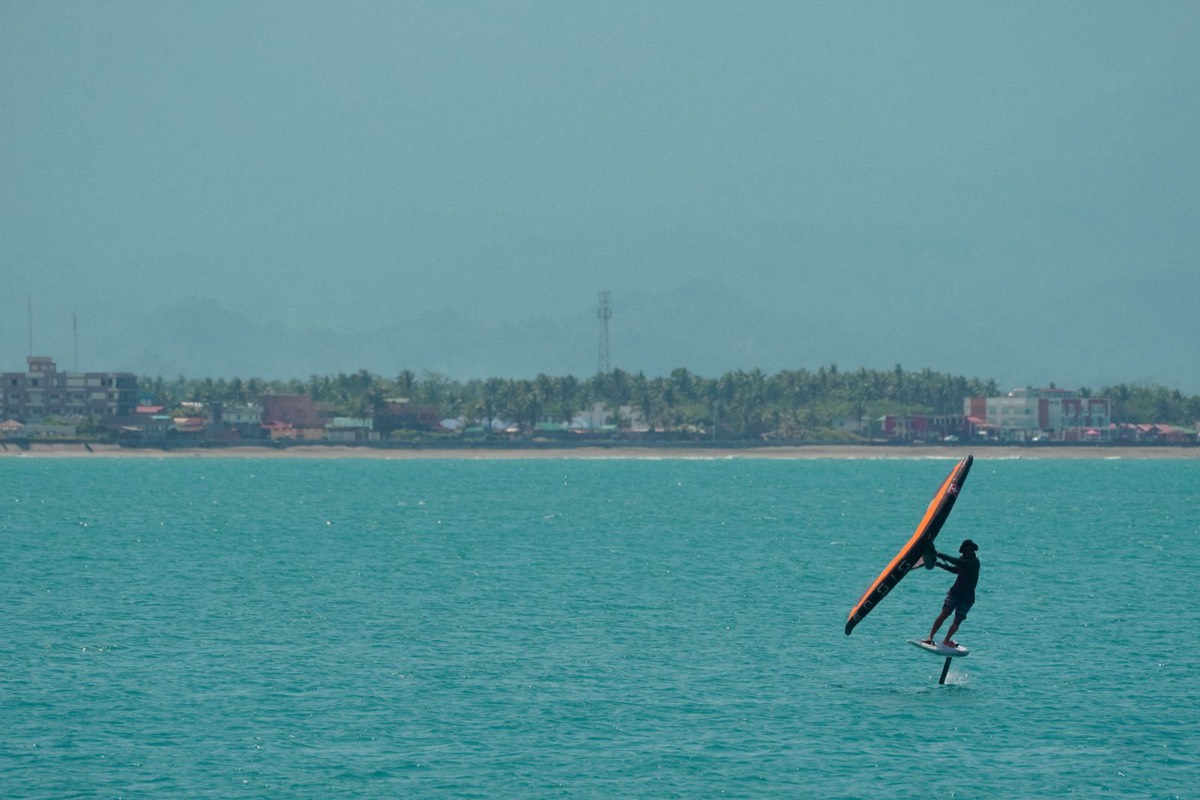 Parawingfoilare i silhuett mot turkost vatten